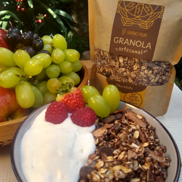 Imagem de granola artesanal sendo utilizada em uma tijela com iogurte, morango e uva